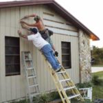 2 men standing on a ladder