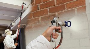 worker using paint sprayer on interior walls