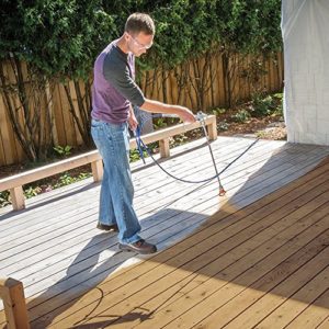 Working man spraying a deck